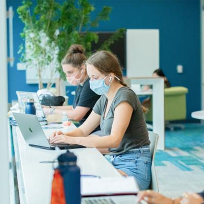 Students studying in the library socially distanced and wearing masks.
