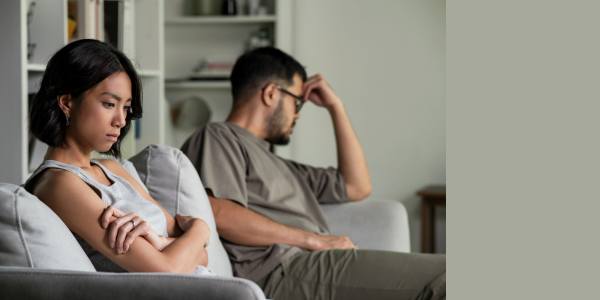 Two people sitting on a couch next to each other, but not looking at or engaging with each other