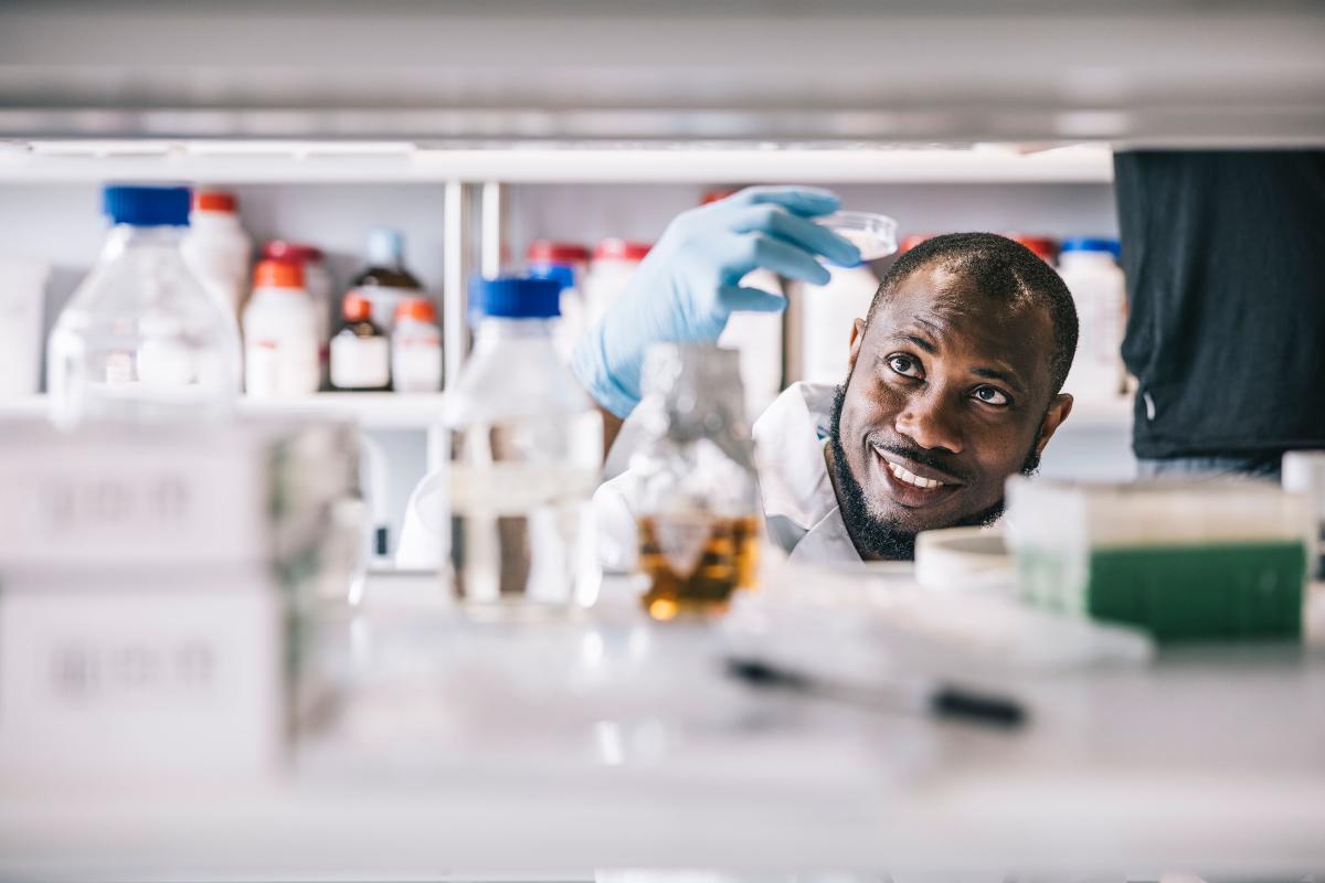 man in lab looking into petry dish